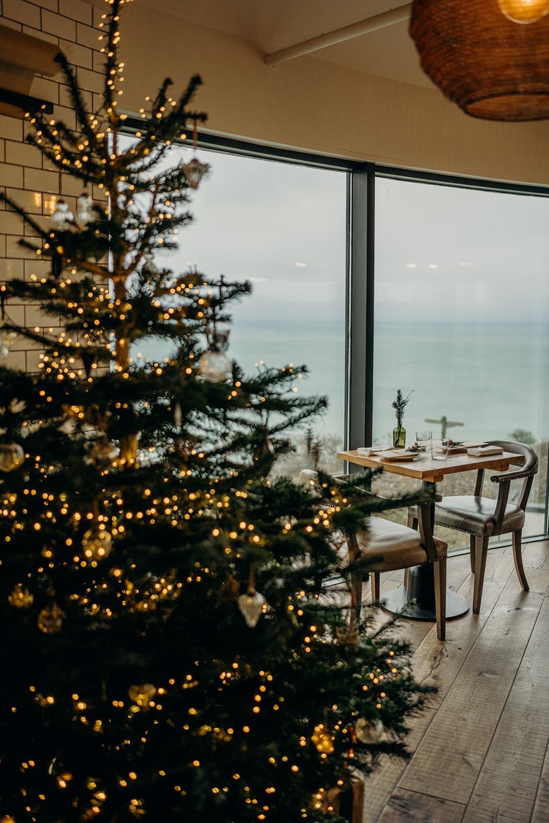 Christmas tree beside a table laid for lunch overlooking the sea