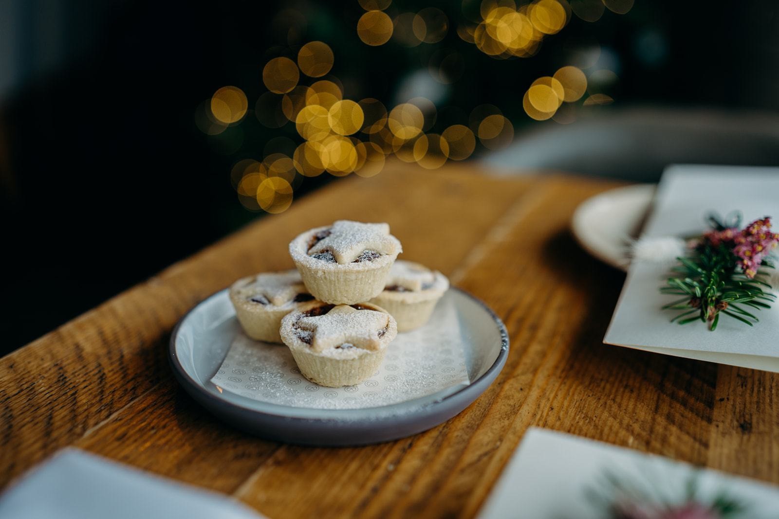 Mince pies dusted with icing sugar beside Christmas cards